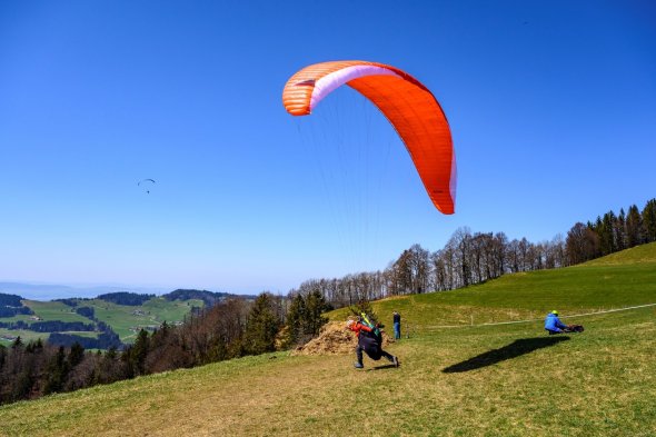 A hang glider takes off from a wooden ramp on a mountain